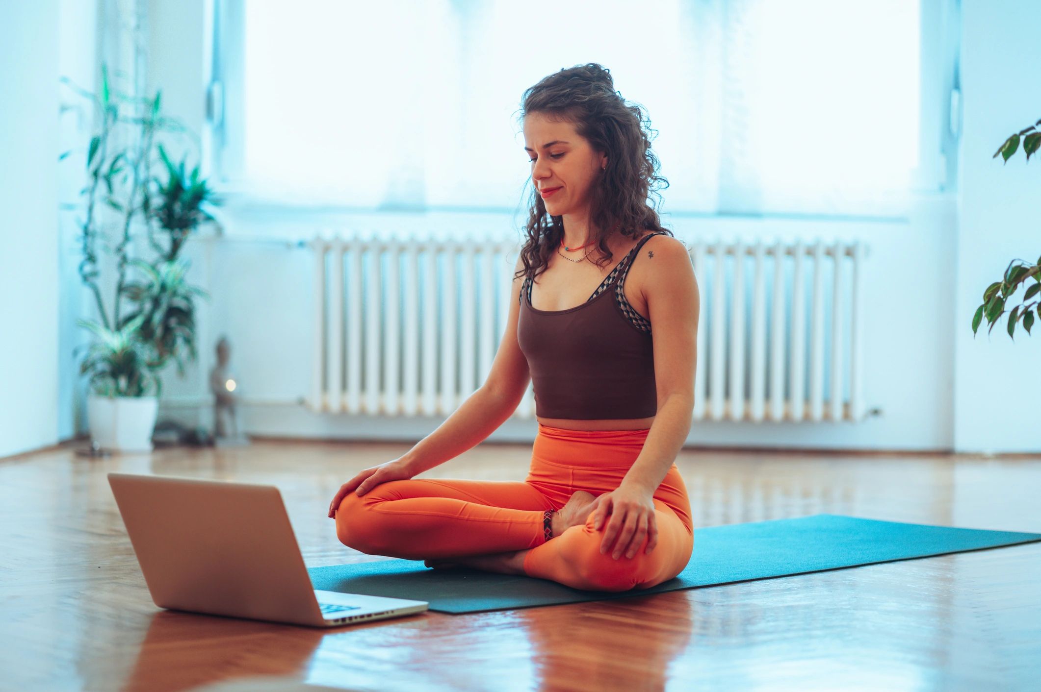 Yoga instructor seated in lotus pose leading an online session